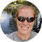 A small, low-resolution profile photo shows a man wearing sunglasses and a cap outdoors near water, used on the Off Leash K9 Training Springfield, MO site.